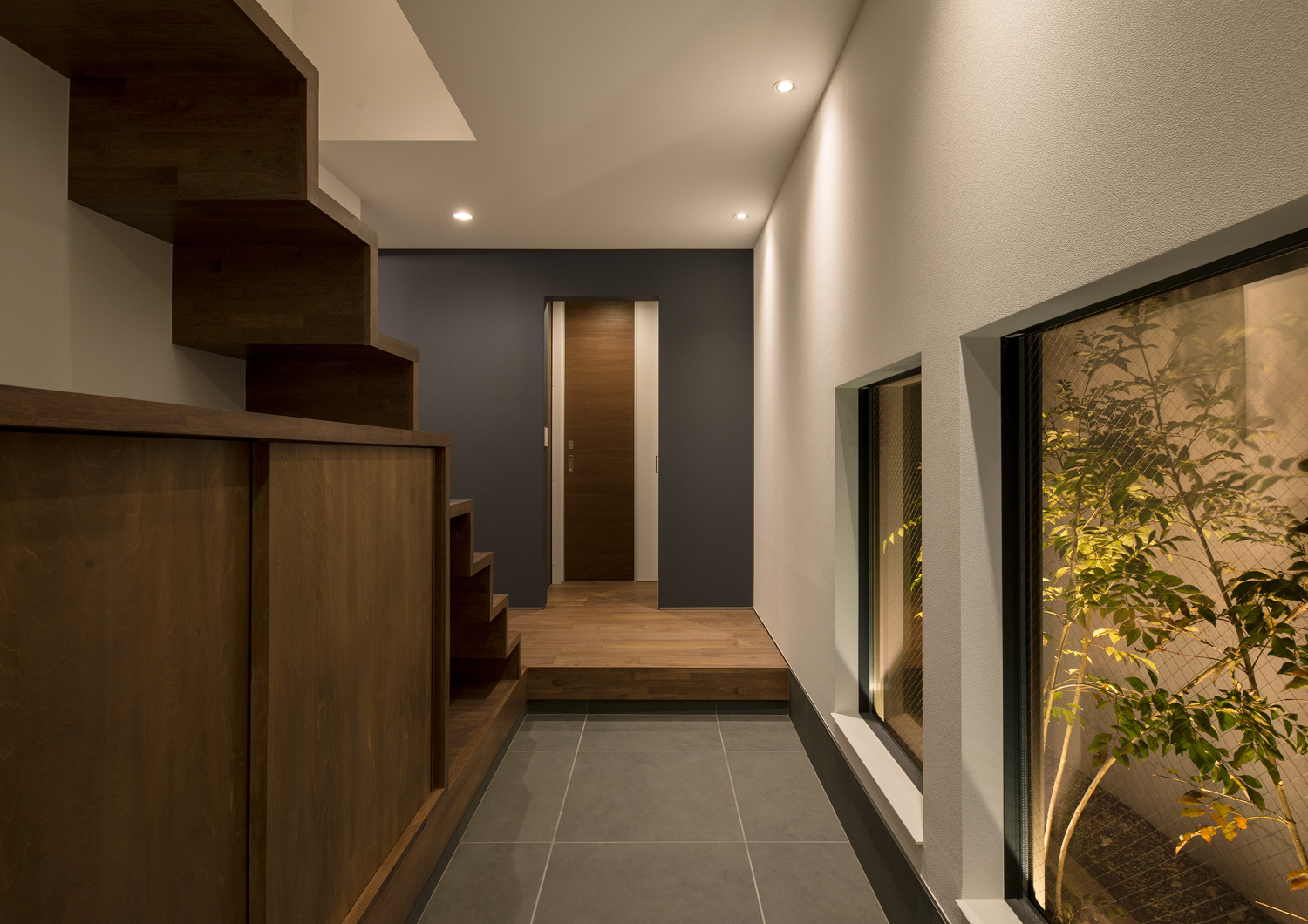 窓からライトアップされた植栽が見えるタイル貼りの玄関・デザイン住宅 注文住宅・デザイン住宅建築実例_『CASE596 【edge】』_玄関