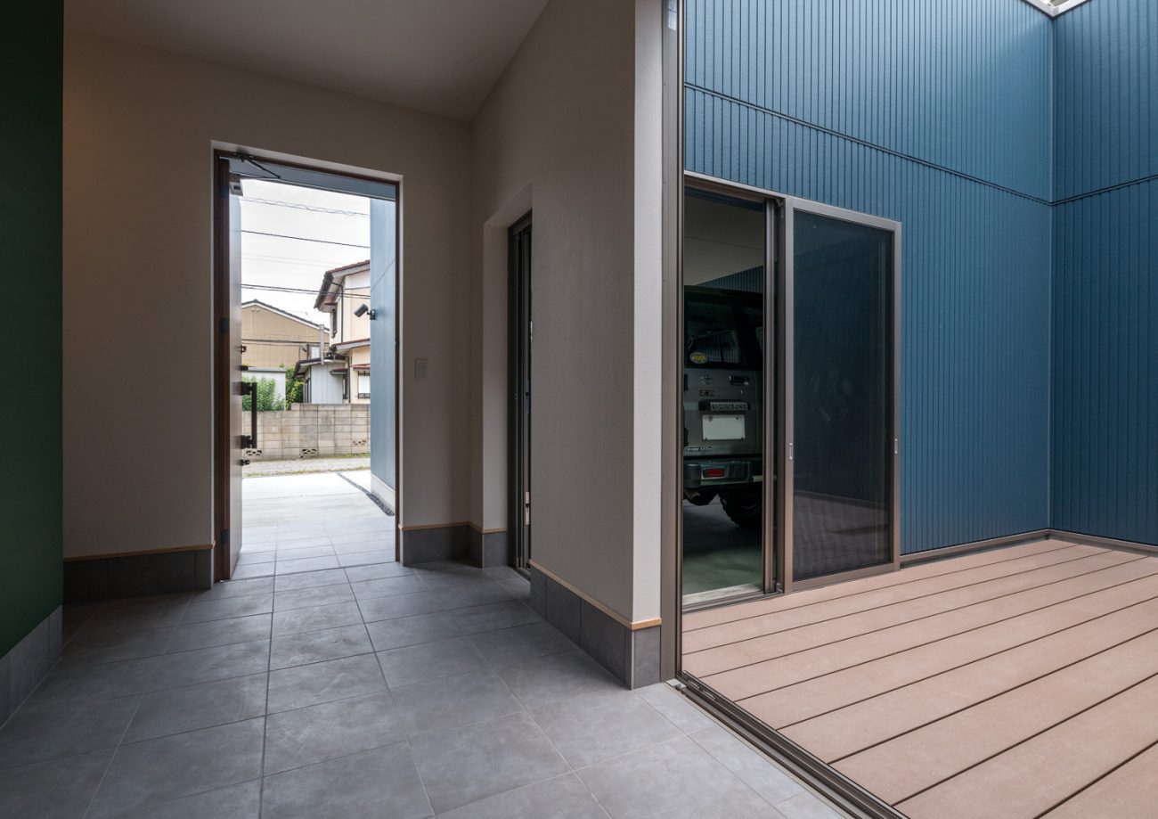 ウッドデッキの中庭と繋がる、玄関扉が開かれた土間の玄関・デザイン住宅 注文住宅・デザイン住宅建築実例_『CASE601 ドマノイエ』_玄関