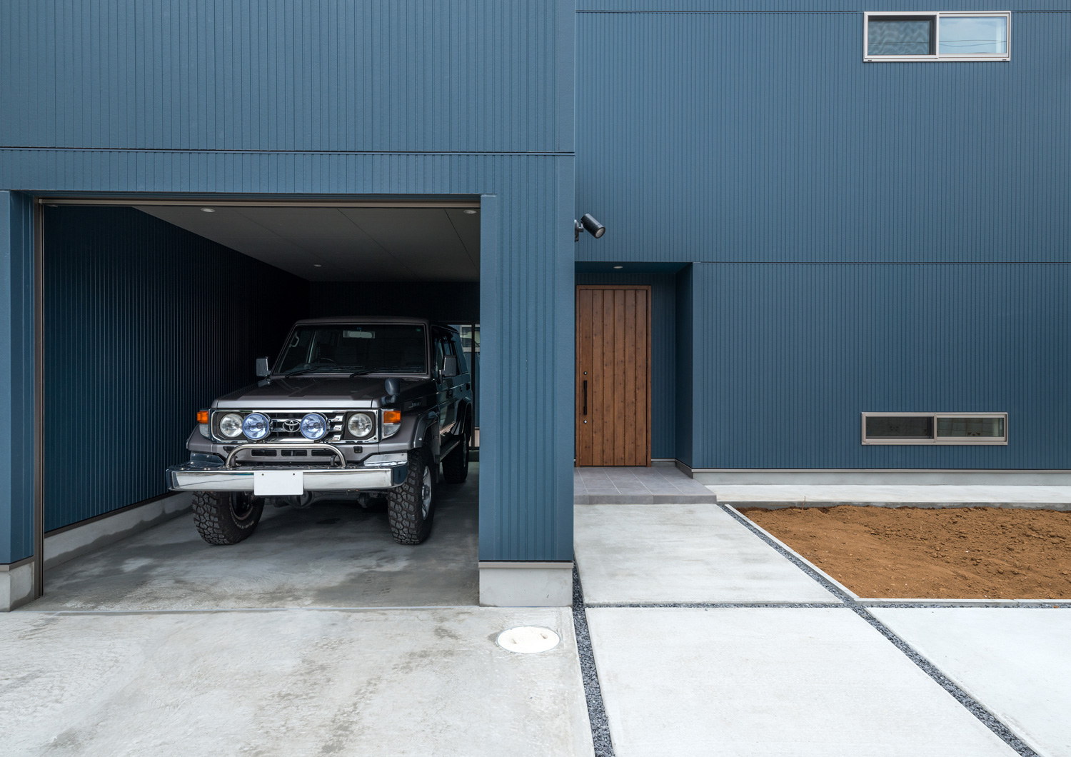 青い外壁でコンクリートのアプローチがあるガレージハウス・デザイン住宅 注文住宅・デザイン住宅建築実例_『CASE601 ドマノイエ』_ガレージ