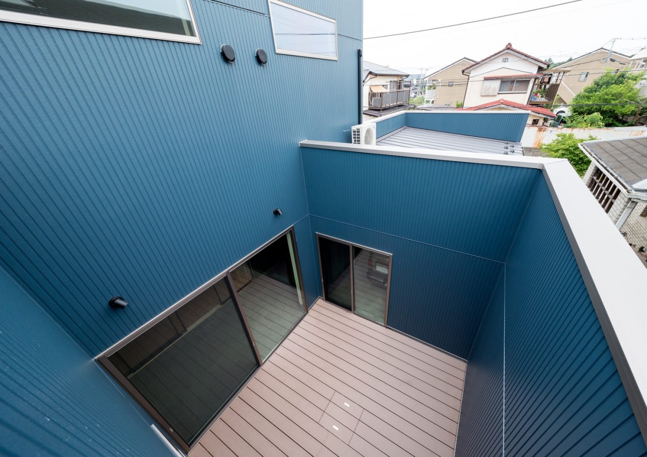 青い壁に囲まれたウッドデッキの中庭を上から見た様子・デザイン住宅 注文住宅・デザイン住宅建築実例_『CASE601 ドマノイエ』_中庭