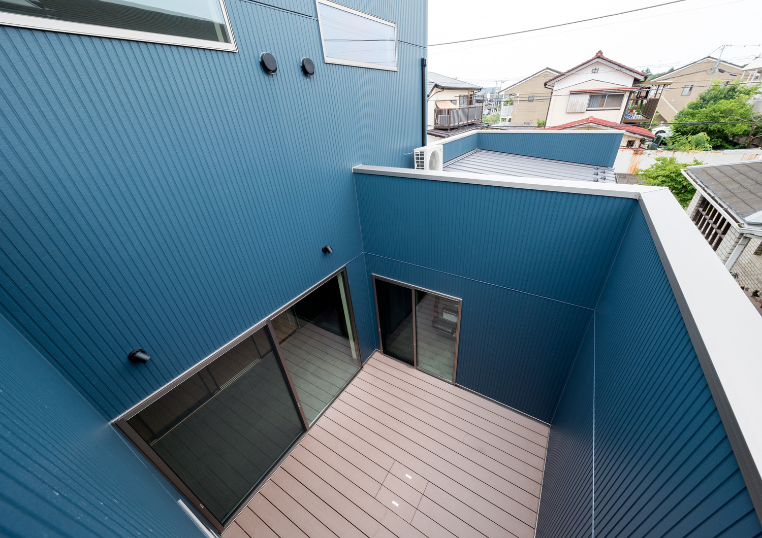 青い壁に囲まれたウッドデッキの中庭を上から見た様子・デザイン住宅 注文住宅・デザイン住宅建築実例_『CASE601 ドマノイエ』_中庭