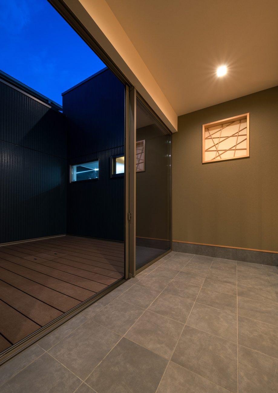 ウッドデッキの中庭とフラットに繋がるグレーのタイルの玄関・デザイン住宅 注文住宅・デザイン住宅建築実例_『CASE601 ドマノイエ』_中庭