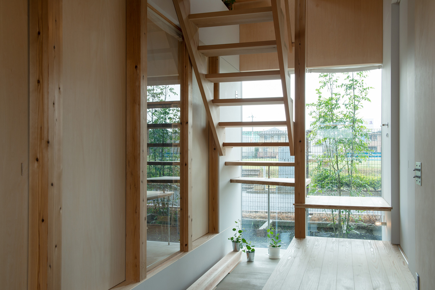 スケルトン階段越しにシンボルツリーが見える窓がある土間の玄関・デザイン住宅 注文住宅・デザイン住宅建築実例_『CASE605 切妻のsign』_玄関