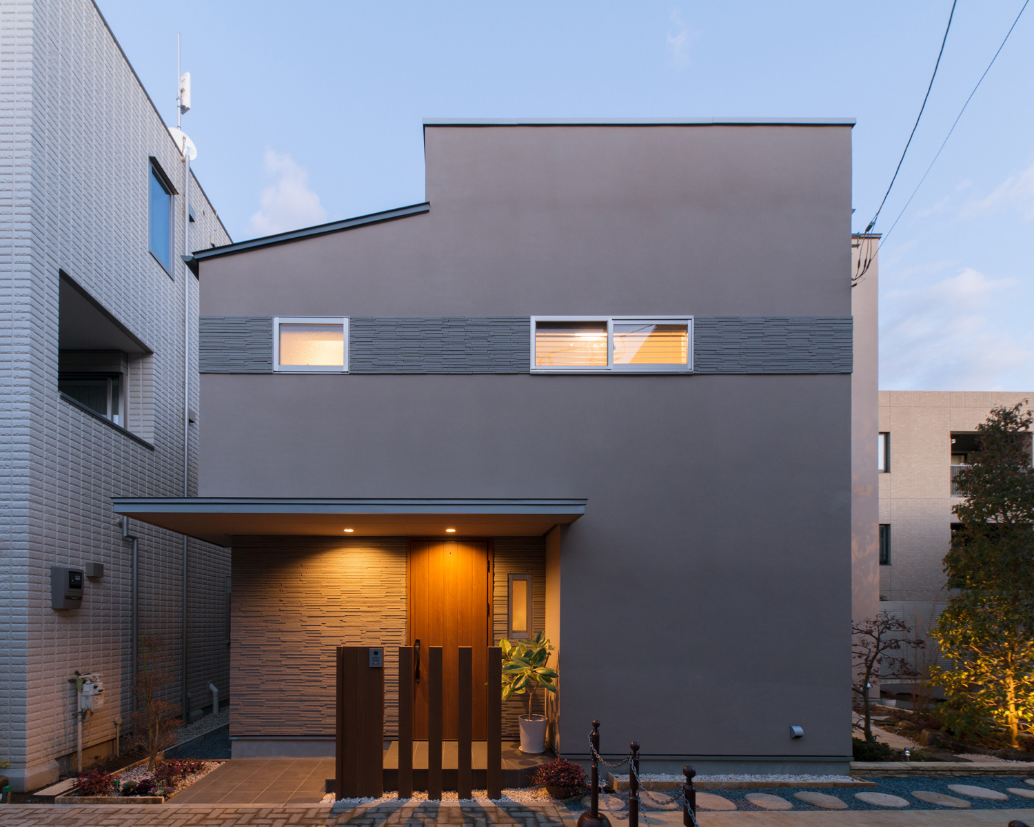 玄関の庇にダウンライトが取り付けられた、小さな窓が一直線に並んだ外観の家・デザイン住宅 注文住宅・デザイン住宅建築実例_『CASE608 和みの住処』_外観