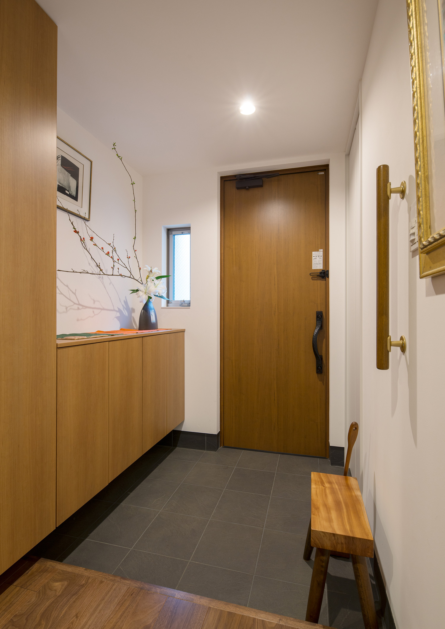 木のシューズボックスを置いた、木の玄関扉があるタイルの玄関・デザイン住宅 注文住宅・デザイン住宅建築実例_『CASE608 和みの住処』_玄関