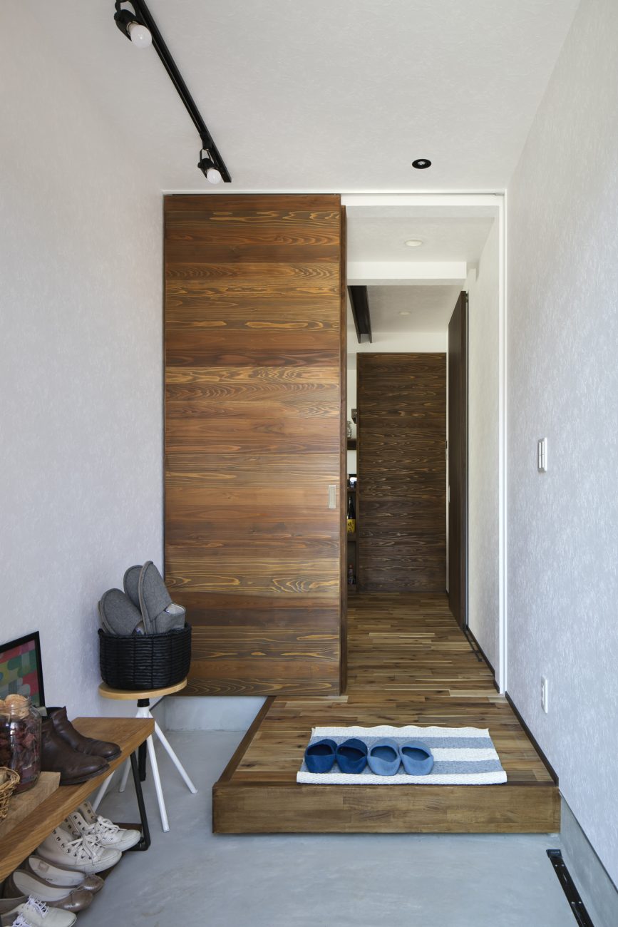 モルタルの玄関の先にフローリングや木の引き戸のあるフロアが広がる様子・デザイン住宅 注文住宅・デザイン住宅建築実例_『CASE610 Lagom hus　ちょうどいい家』_玄関