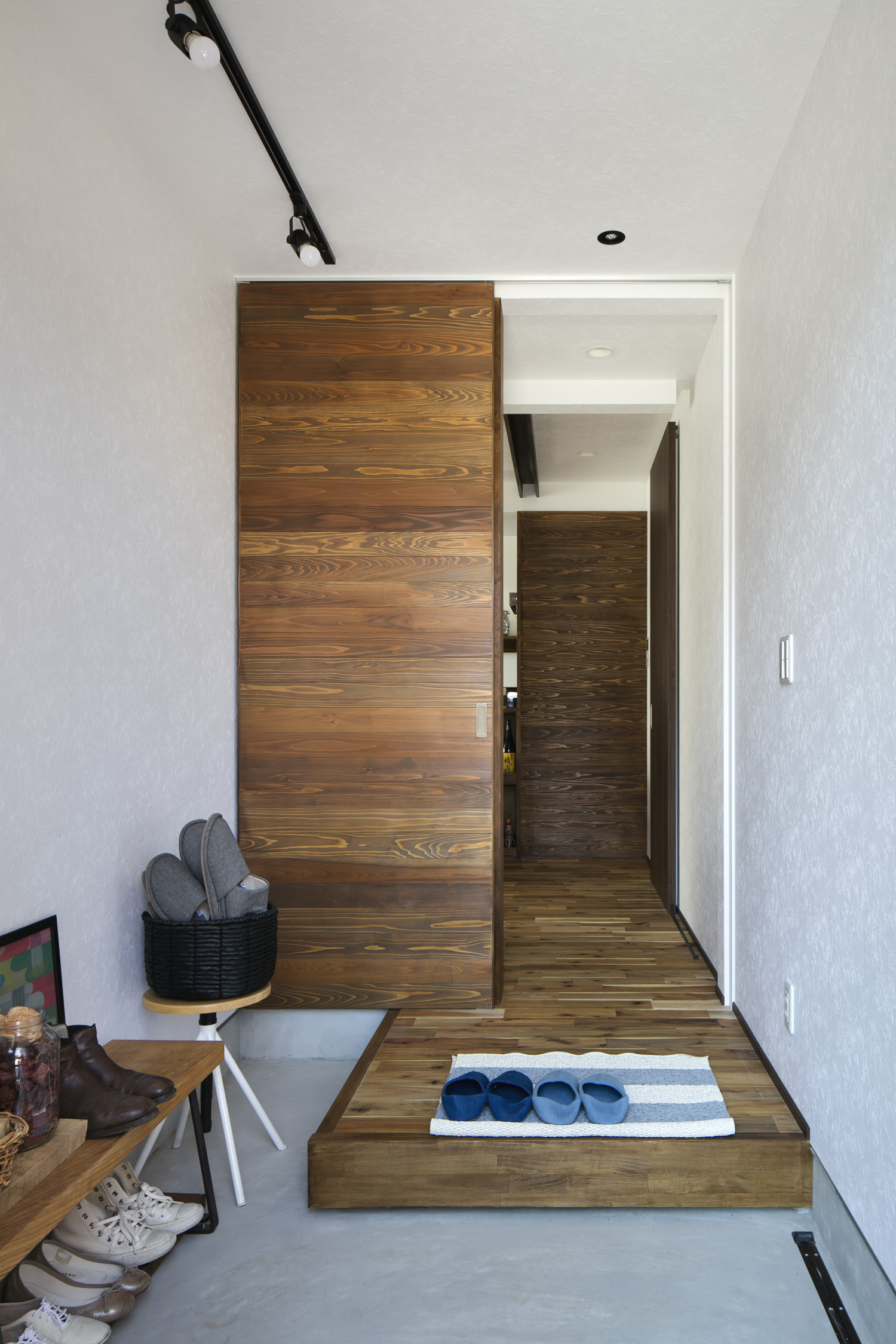 モルタルの玄関の先にフローリングや木の引き戸のあるフロアが広がる様子・デザイン住宅 注文住宅・デザイン住宅建築実例_『CASE610 Lagom hus　ちょうどいい家』_玄関