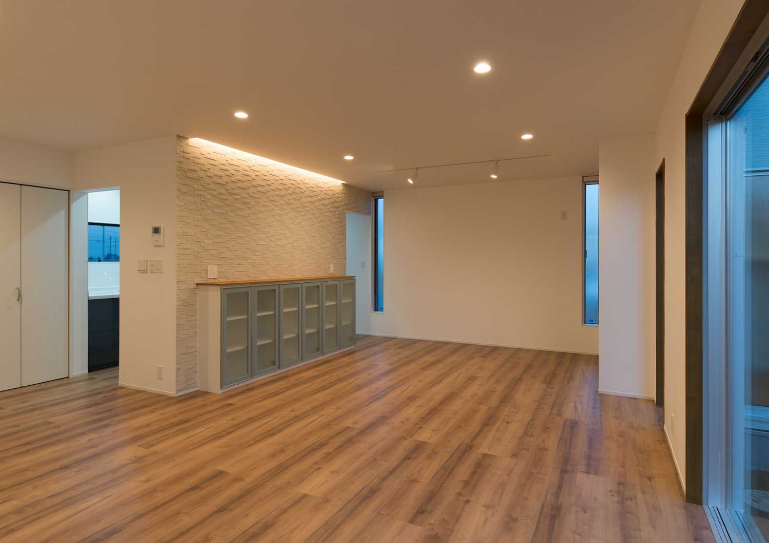 壁際の間接照明と、天井のダウンライトに照らされたLDK・デザイン住宅 注文住宅・デザイン住宅建築実例_『CASE611 黒曜×石英』_LDK