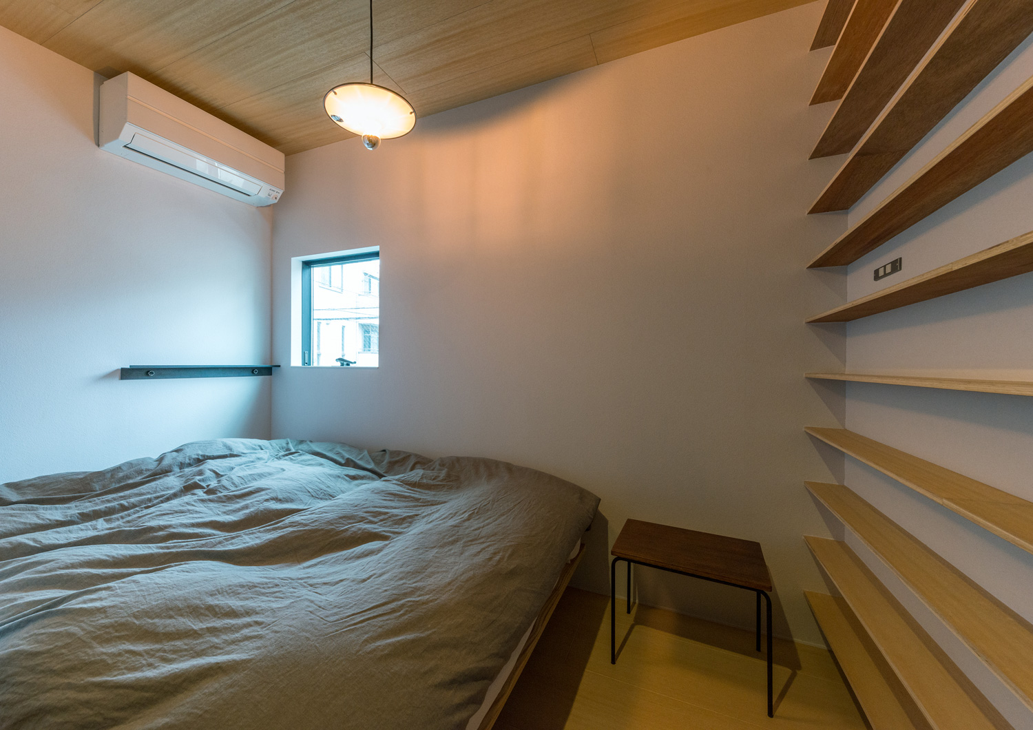 壁一面に木製の棚を取り付けた、グレーのベッドが置かれた寝室・デザイン住宅 注文住宅・デザイン住宅建築実例_『CASE612 たなのいえ』_寝室