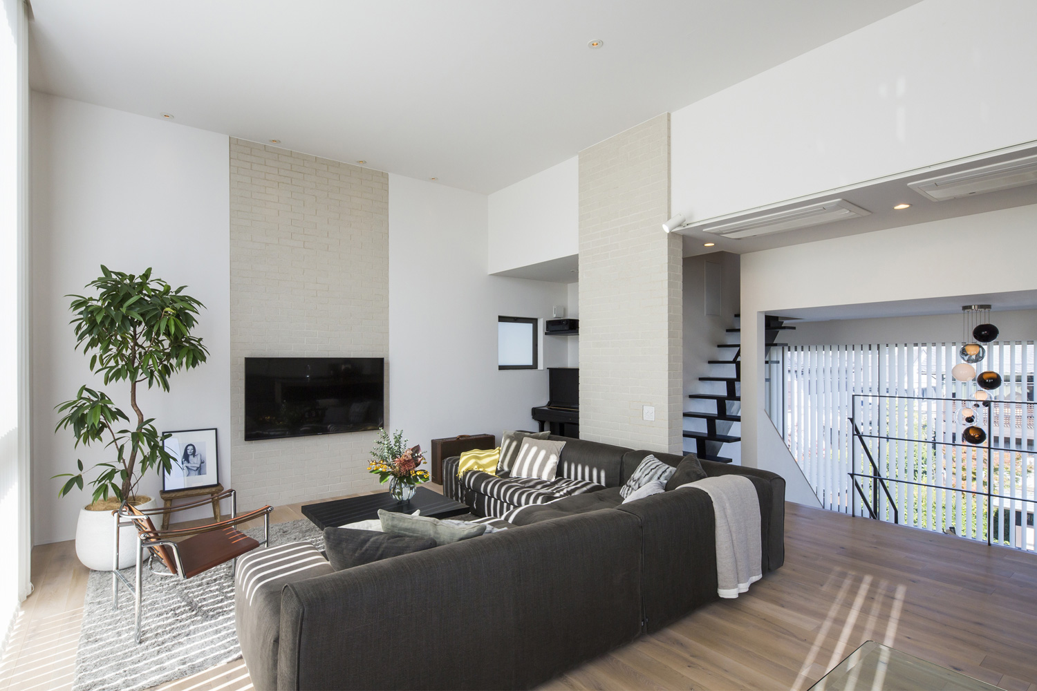 壁掛けテレビの前にL字ソファーを置いた、観葉植物のあるLDK・デザイン住宅 注文住宅・デザイン住宅建築実例_『CASE614 『Skip』』_LDK