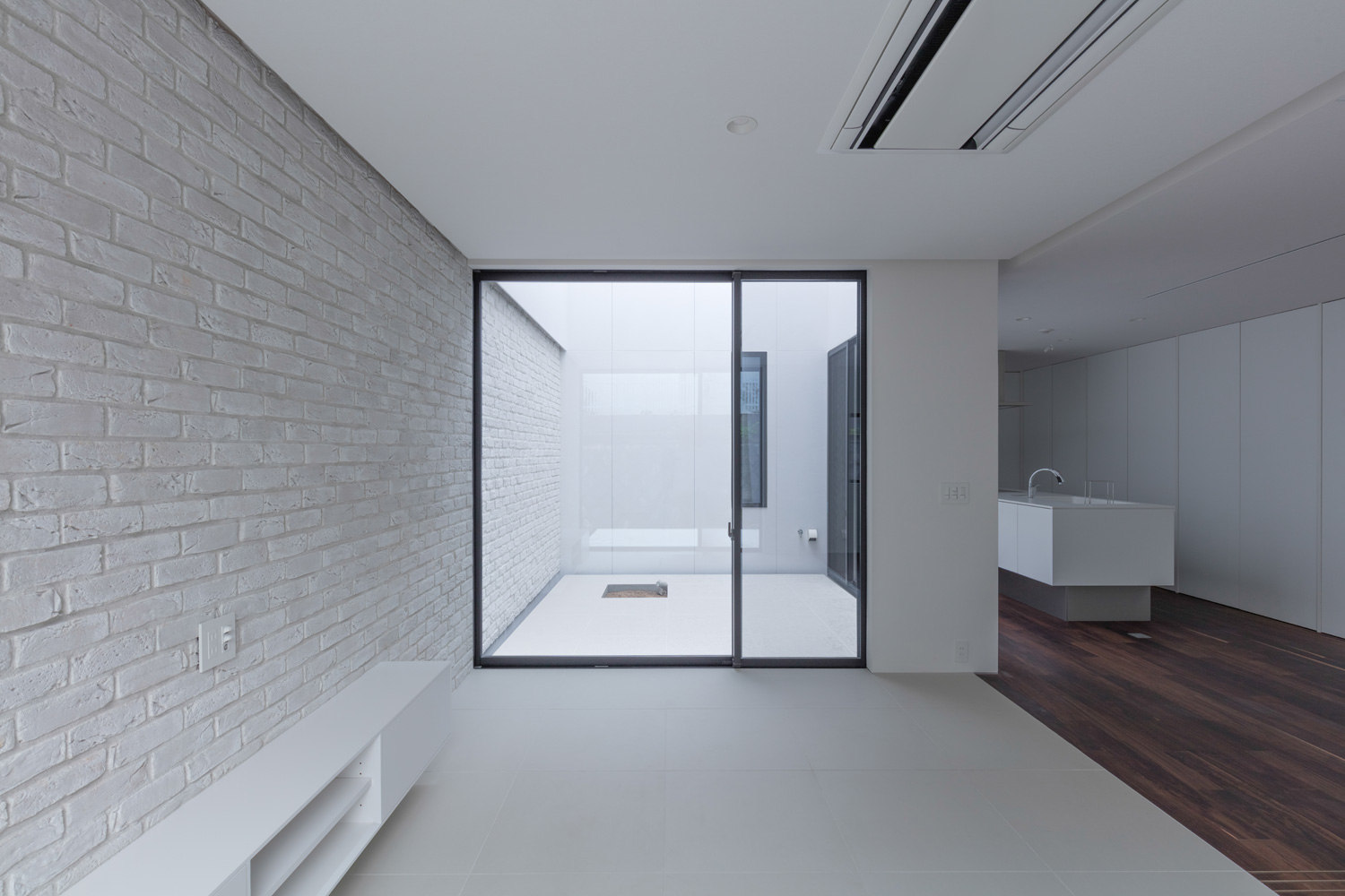 白いタイル床で、壁付けの白いテレビボードが設けられた中庭に繋がる窓があるLDK・デザイン住宅 注文住宅・デザイン住宅建築実例_『CASE616 HOUSE.FLOAT』_LDK