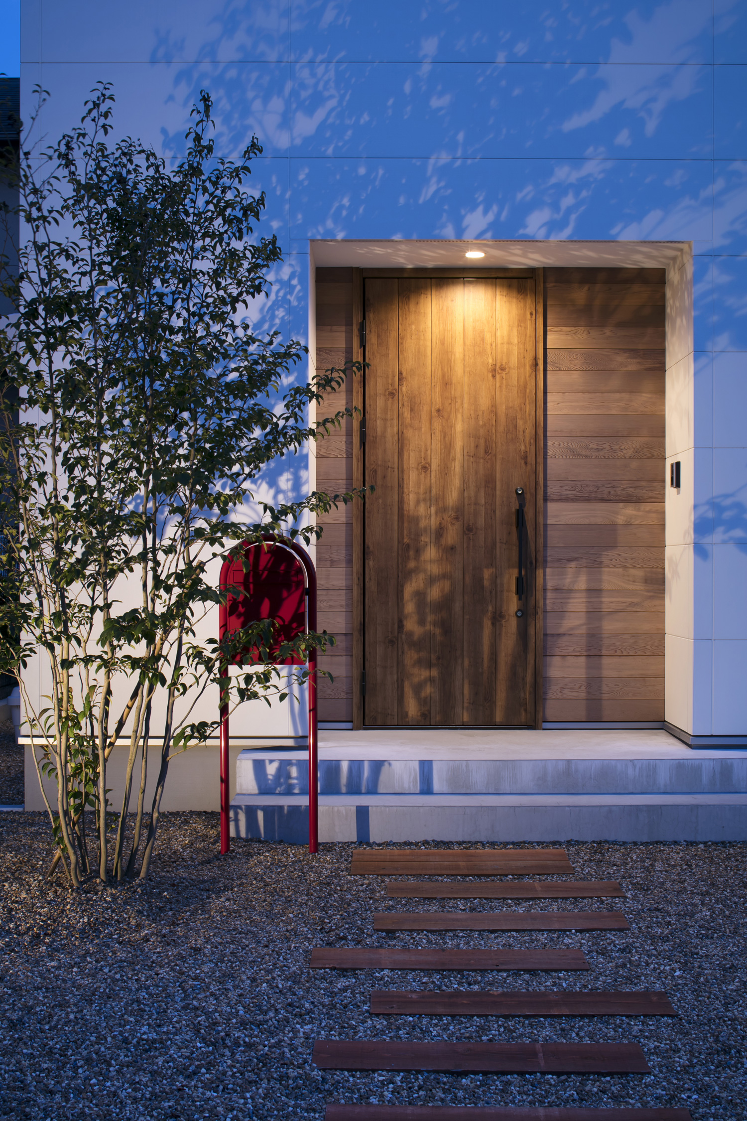 軒天井のダウンライトに照らされる木の玄関扉が付いた玄関ポーチ・デザイン住宅 注文住宅・デザイン住宅建築実例_『CASE619 Hoccori』_外観