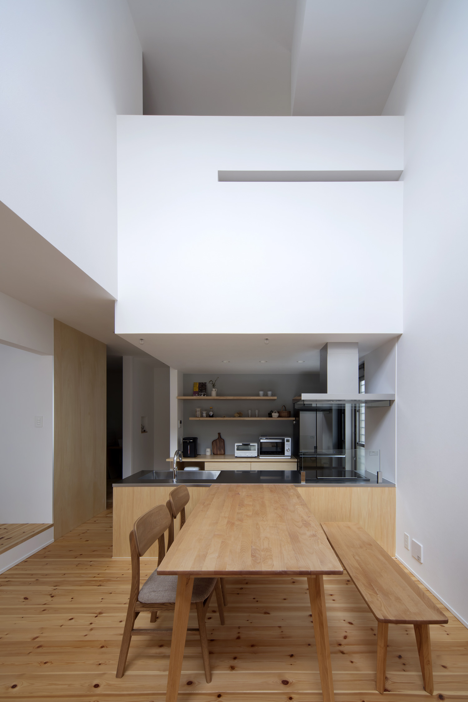 木製のダイニングテーブルやベンチが置かれた吹き抜けのLDK・デザイン住宅 注文住宅・デザイン住宅建築実例_『CASE619 Hoccori』_LDK