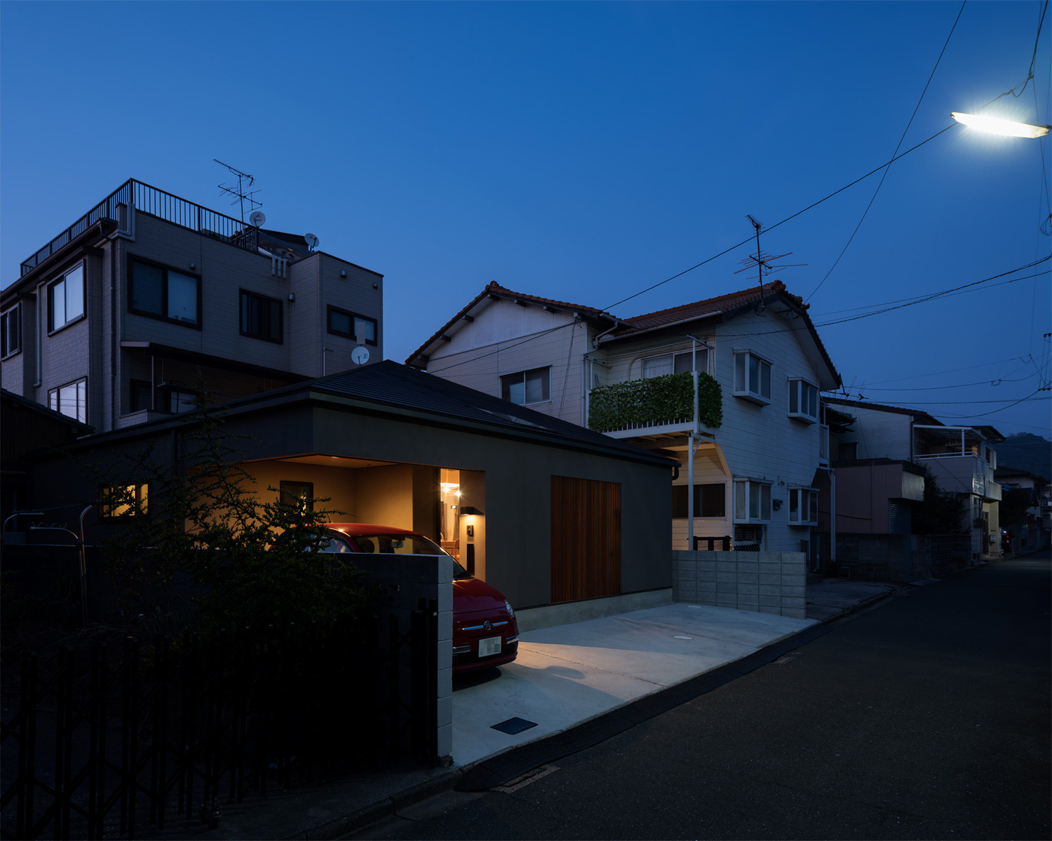 玄関に明かりがついた、車が一台止められた平屋住宅を斜めから見た様子・デザイン住宅 注文住宅・デザイン住宅建築実例_『CASE622 fit』_外観