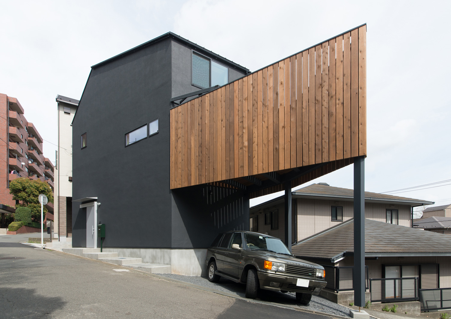 木のバルコニーの下に黒い車が止められた黒い外壁の住宅の外観・デザイン住宅 注文住宅・デザイン住宅建築実例_『CASE626 Triangle』_外観