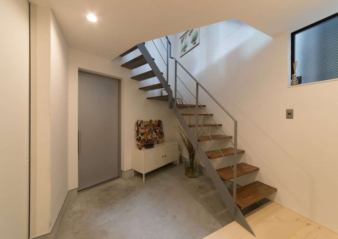 木製のスケルトン階段が横切るモルタルの玄関・デザイン住宅 注文住宅・デザイン住宅建築実例_『CASE626 Triangle』_玄関