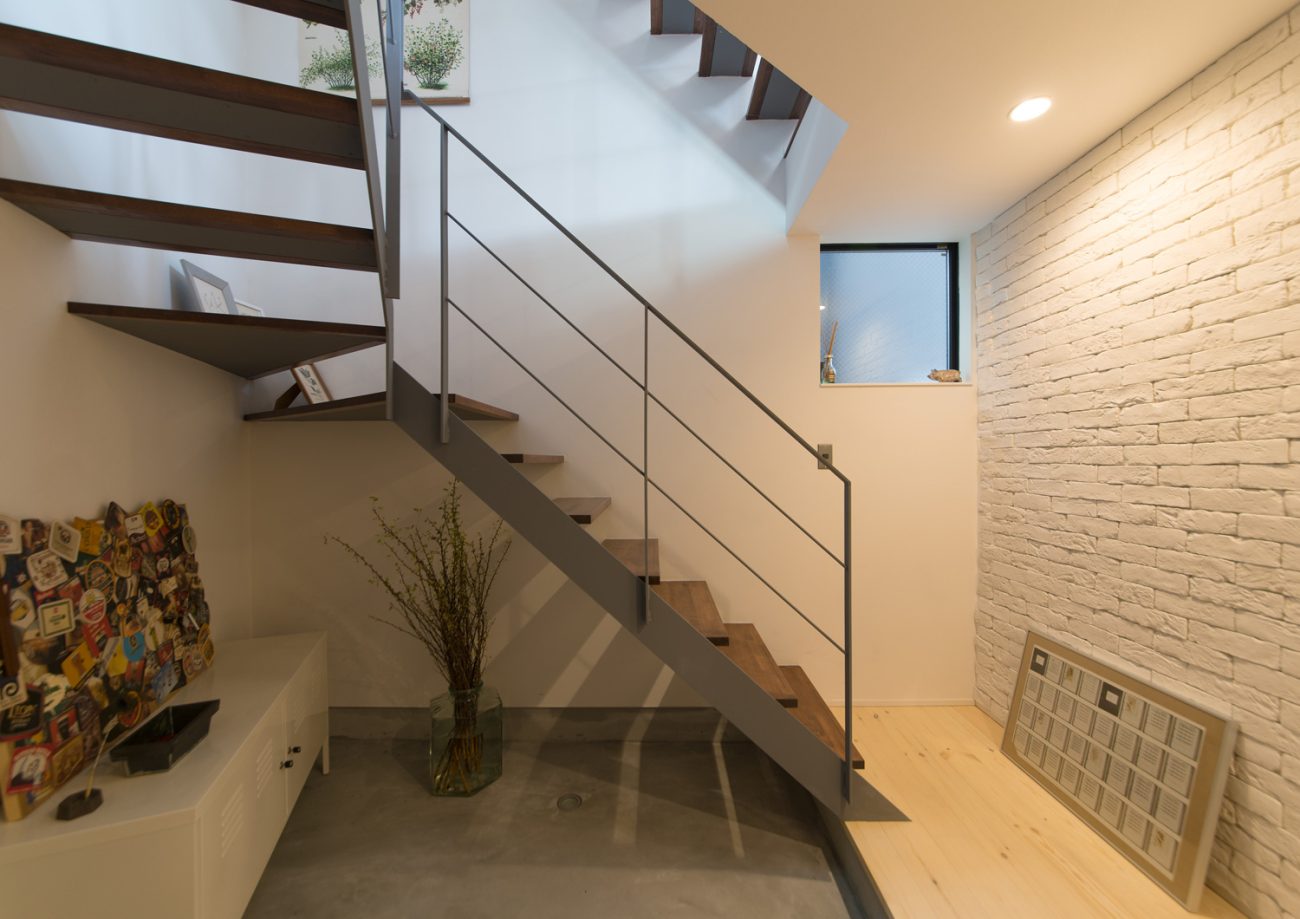 スケルトン階段下のスペースに観葉植物やスチールの白い収納が置かれたモルタルの玄関・デザイン住宅 注文住宅・デザイン住宅建築実例_『CASE626 Triangle』_玄関