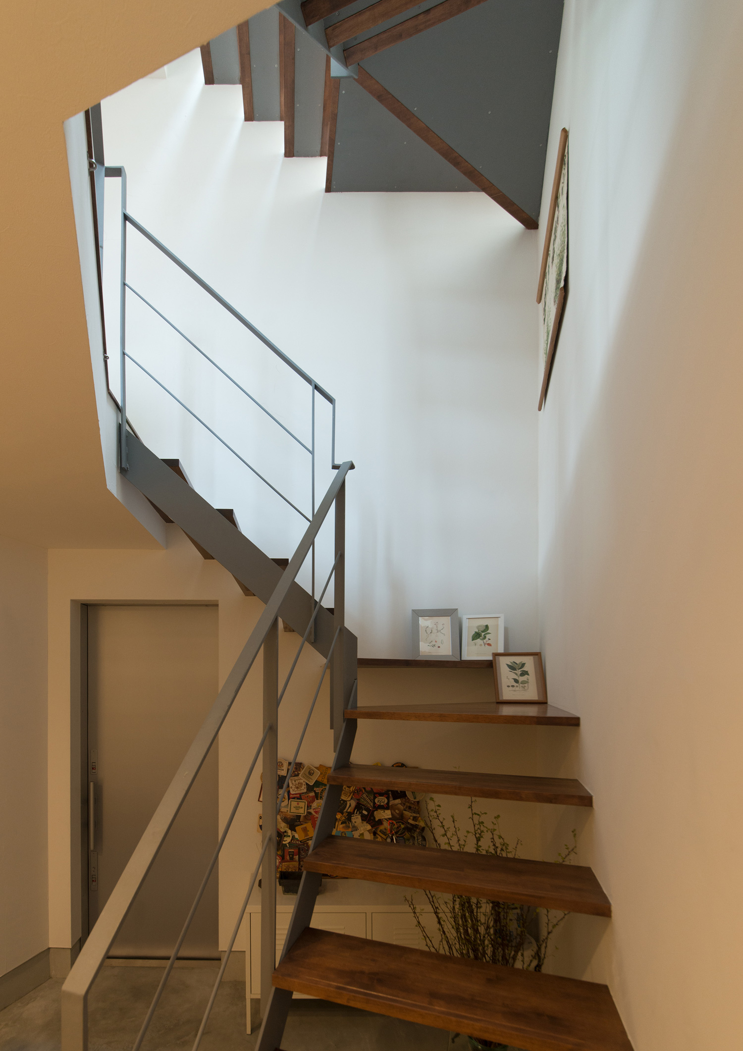 階段下の観葉植物や、踊り場に置かれた写真が見えるスケルトン階段・デザイン住宅 注文住宅・デザイン住宅建築実例_『CASE626 Triangle』_階段