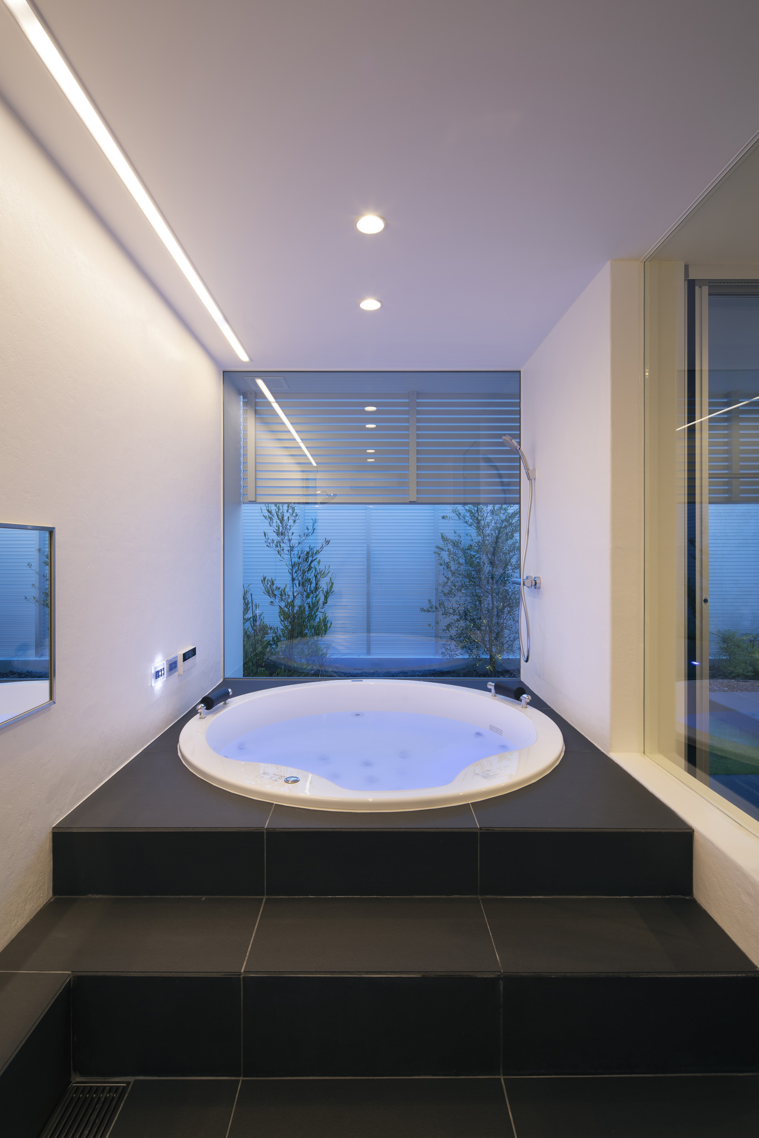 壁に間接照明を取り付けた、中庭が見える丸い浴槽の浴室・デザイン住宅 注文住宅・デザイン住宅建築実例_『CASE627 HOUSE . GARAGE HOUSE』_浴室・洗面所