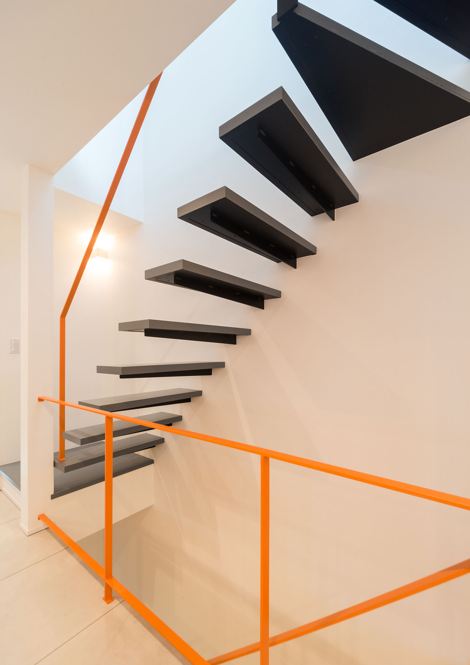 オレンジ色のシャープな手すりを取り付けた黒い浮いたデザインの階段・デザイン住宅 注文住宅・デザイン住宅建築実例_『CASE460 三色　～さんしき～』_階段