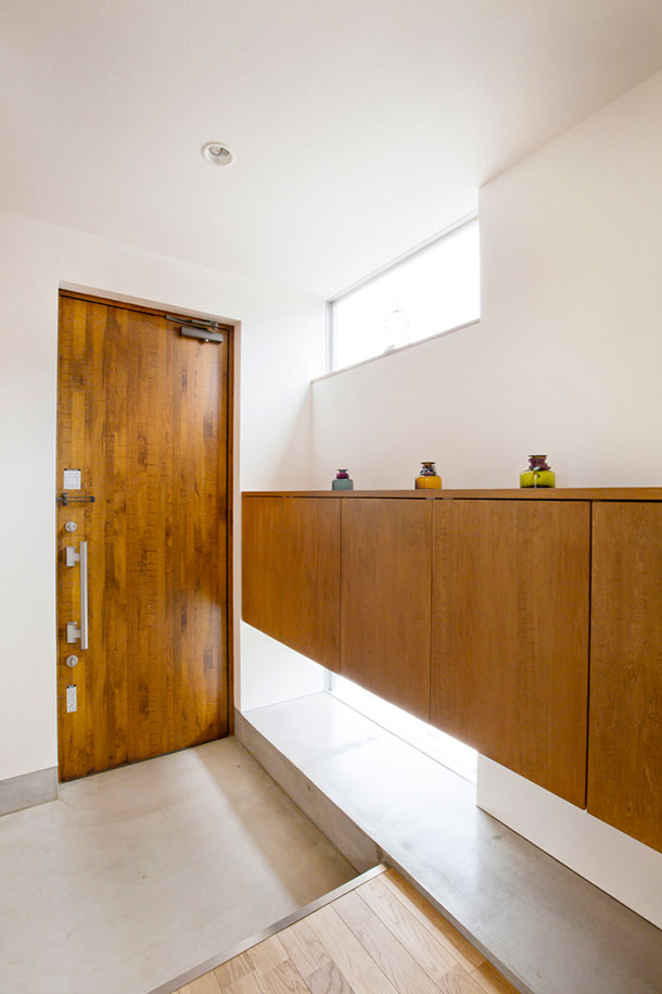 木の玄関扉と木のシューズボックスがあるシンプルな玄関・デザイン住宅