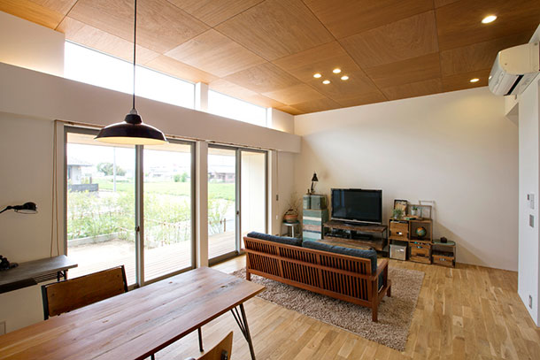 ウッドデッキの縁側に面した大きな窓がある木目の天井の明るいLDK・デザイン住宅