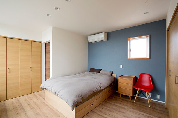 青いアクセントクロスを取り付けたクローゼット付きの寝室・デザイン住宅