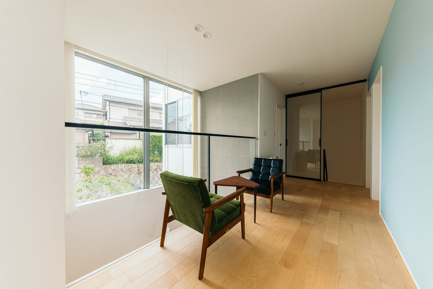 水色のアクセントクロスがありテーブルと椅子が置かれた吹き抜けに面した空間・ホビールームのある家 注文住宅・デザイン住宅建築実例_『CASE684  ホビールームのある家』_フリースペース