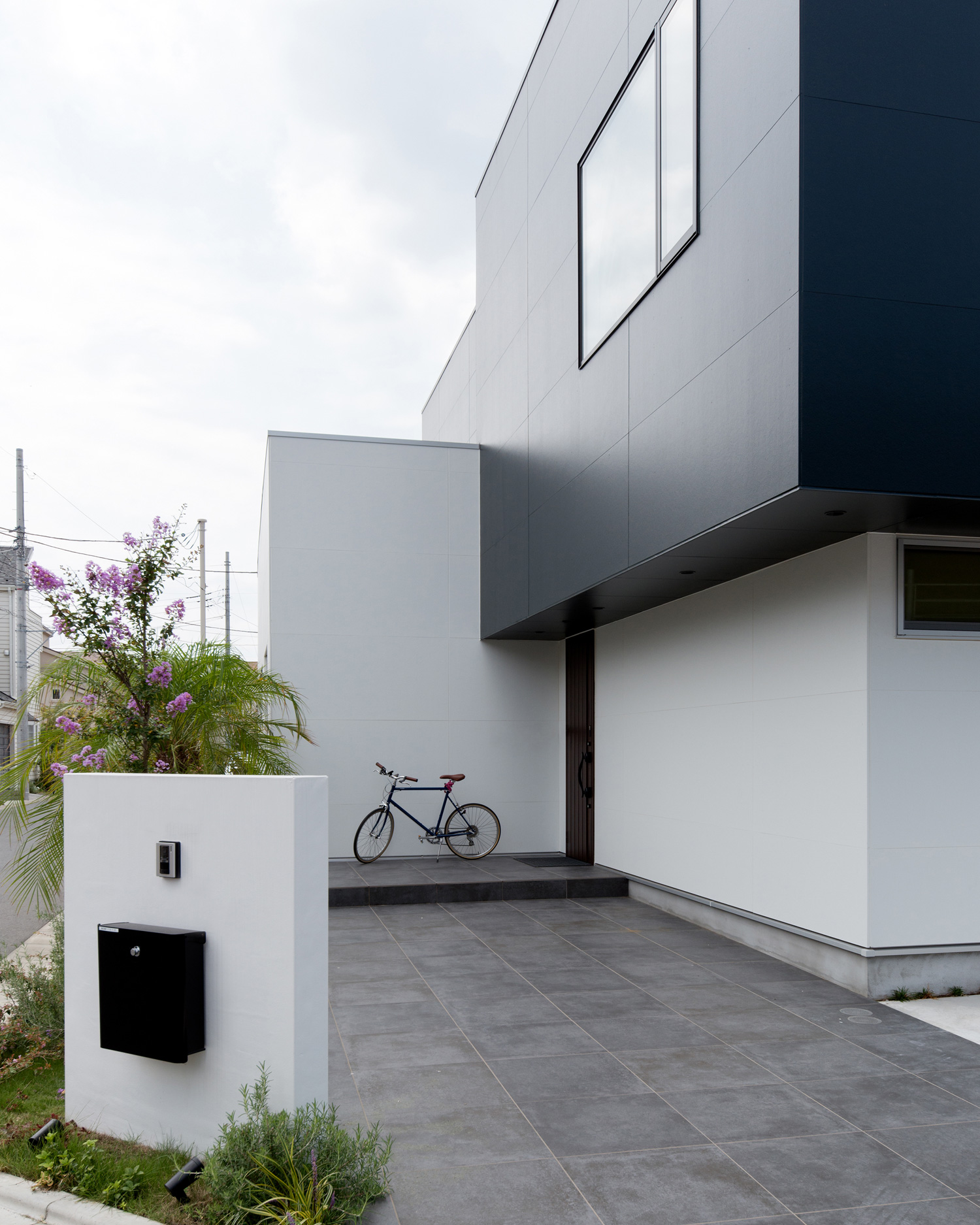 自転車が止められたタイルのアプローチがあるモノトーンの外壁の家・デザイン住宅 注文住宅・デザイン住宅建築実例_『CASE593 CAMP』_外観