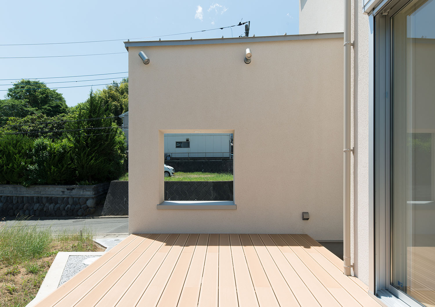 ウッドデッキのテラスを隠すように設けた正方形の開口部を設けた壁・デザイン住宅 注文住宅・デザイン住宅建築実例_『CASE550 three box house』_テラス・バルコニー