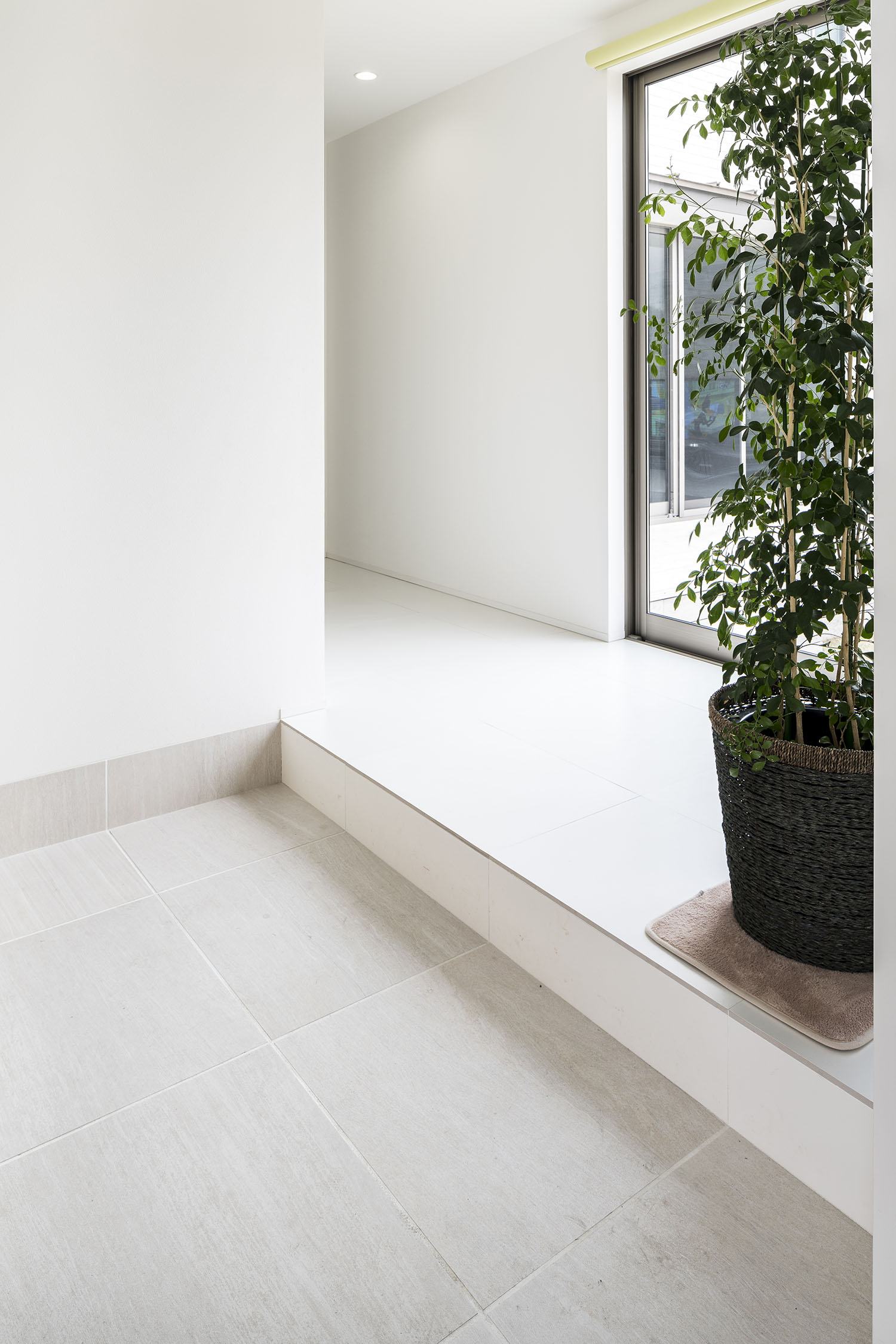 壁や床が白い室内に繋がるタイルの玄関・デザイン住宅 注文住宅・デザイン住宅建築実例_『CASE581 Tcourt』_玄関