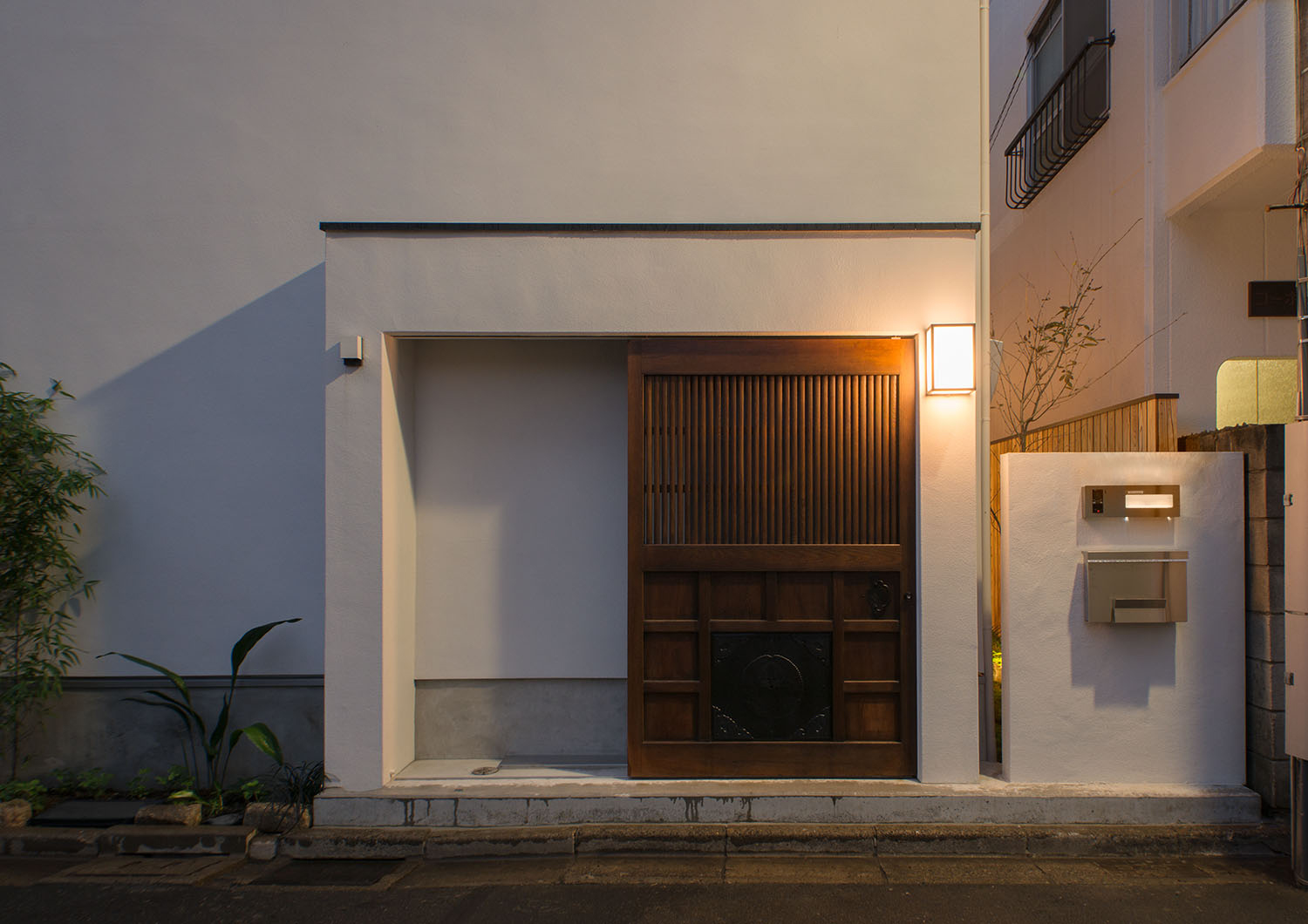 壁に照明が取り付けられた木の引き戸を取り付けた玄関ポーチ・デザイン住宅 注文住宅・デザイン住宅建築実例_『CASE487 立方の家』_外観