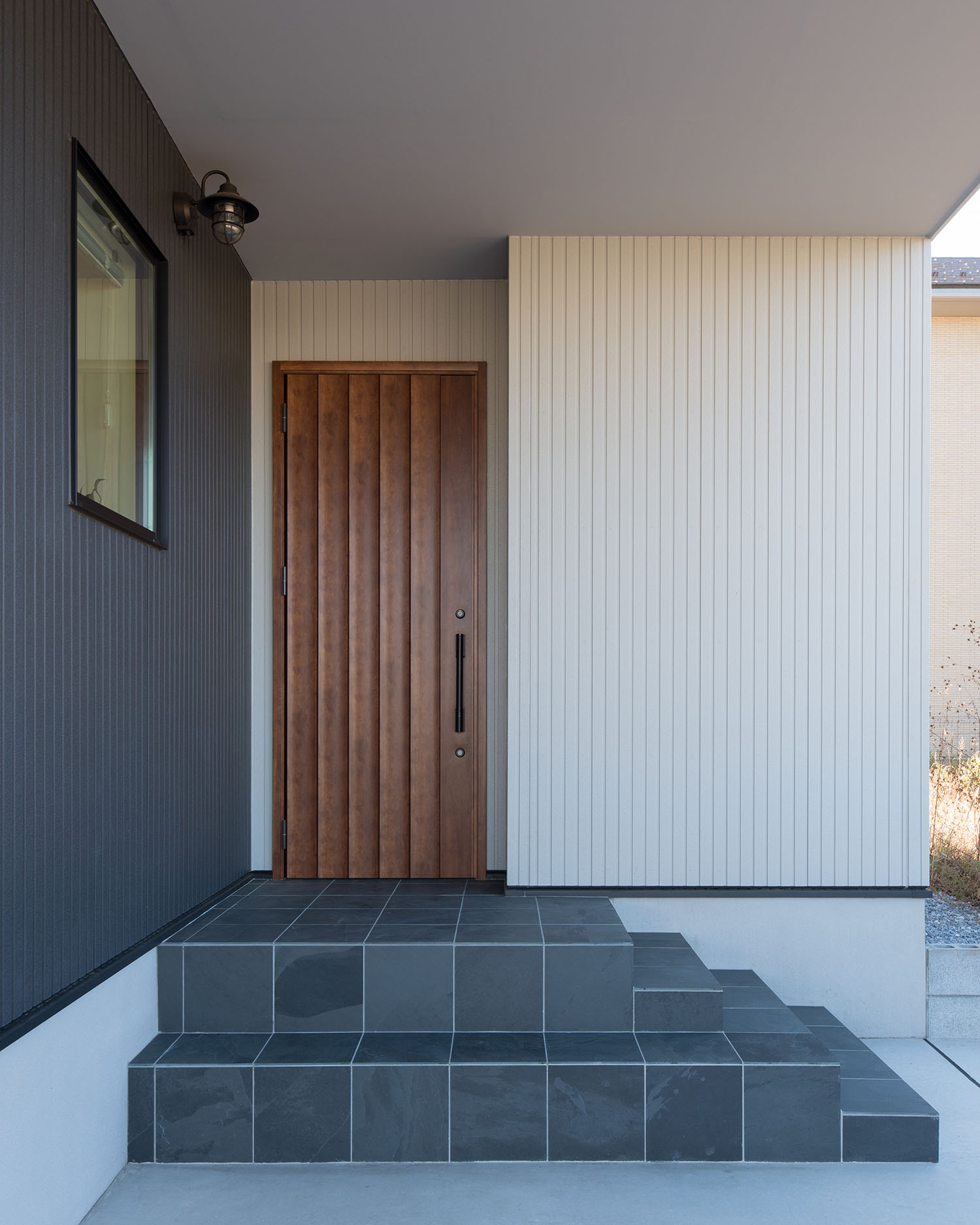 タイルの階段アプローチの先に木目の玄関扉がある家・デザイン住宅 注文住宅・デザイン住宅建築実例_『CASE591 Moist』_外観