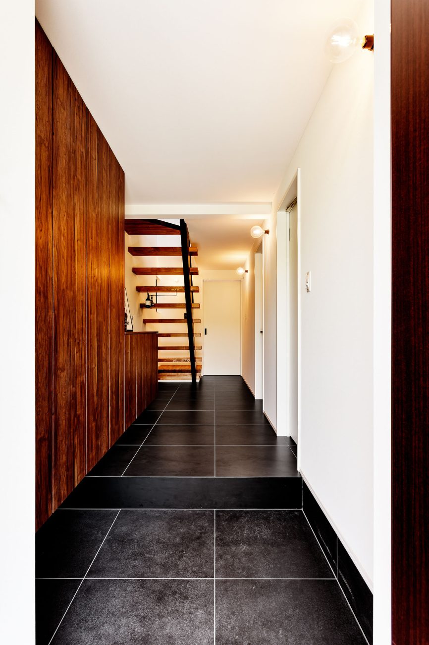 黒いタイル張りで、木製の収納やスケルトン階段が見える玄関・デザイン住宅 注文住宅・デザイン住宅建築実例_『CASE604 “LIKE”』_玄関