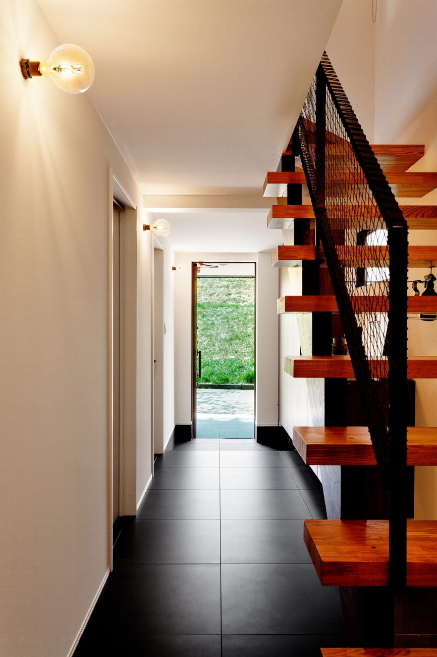 黒いタイル張りの玄関から、外の景色が見える様子・デザイン住宅 注文住宅・デザイン住宅建築実例_『CASE604 “LIKE”』_玄関