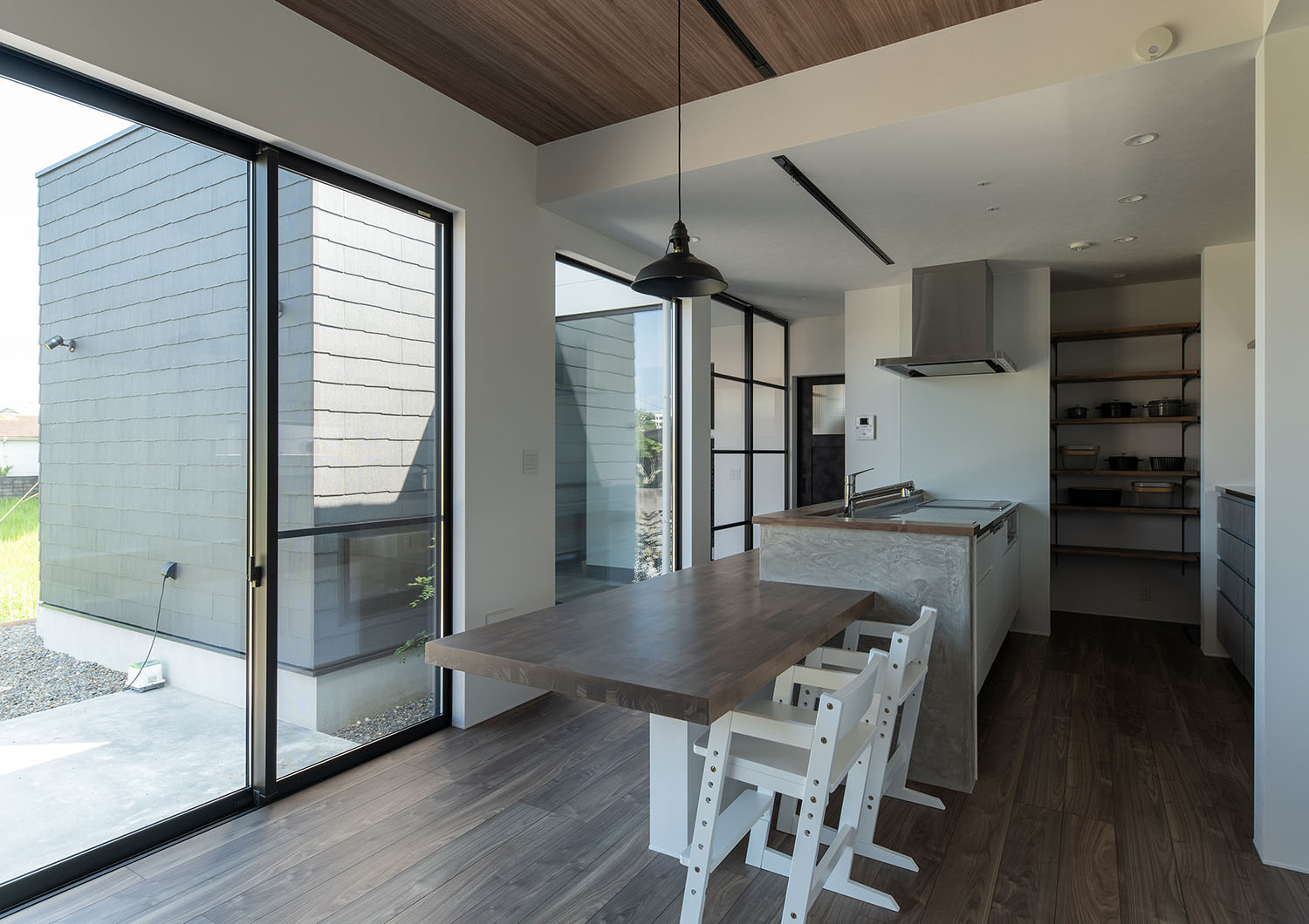 キッチンの奥に食器棚があり、ダイニングテーブルから中庭の様子が見える様子・デザイン住宅 注文住宅・デザイン住宅建築実例_『CASE685 flat scale』_LDK