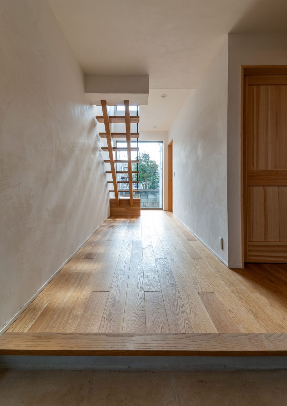 玄関からスケルトン階段越しに窓からの景色が見える様子・デザイン住宅 注文住宅・デザイン住宅建築実例_『CASE690 質感にこだわった完成を楽しむ家』_玄関