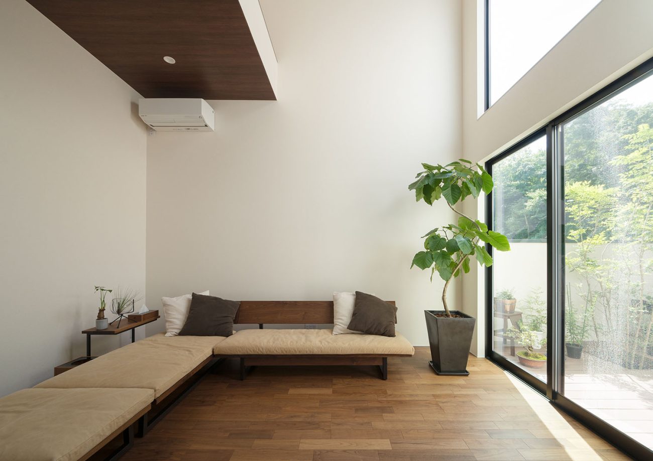 中庭の景色が楽しめるようにソファーが配置された吹き抜けのリビング