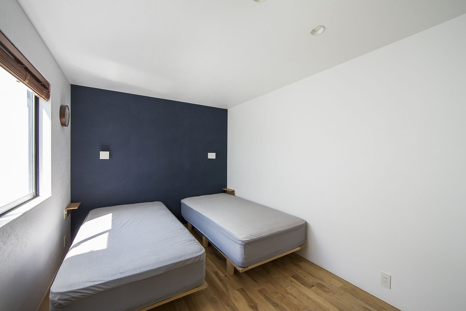 ネイビーのアクセントクロスがあり、グレーのシングルベッドが2台並んだ寝室・フリーダムアーキテクツの事例 注文住宅・デザイン住宅建築実例_『CASE706 Re:load』_寝室