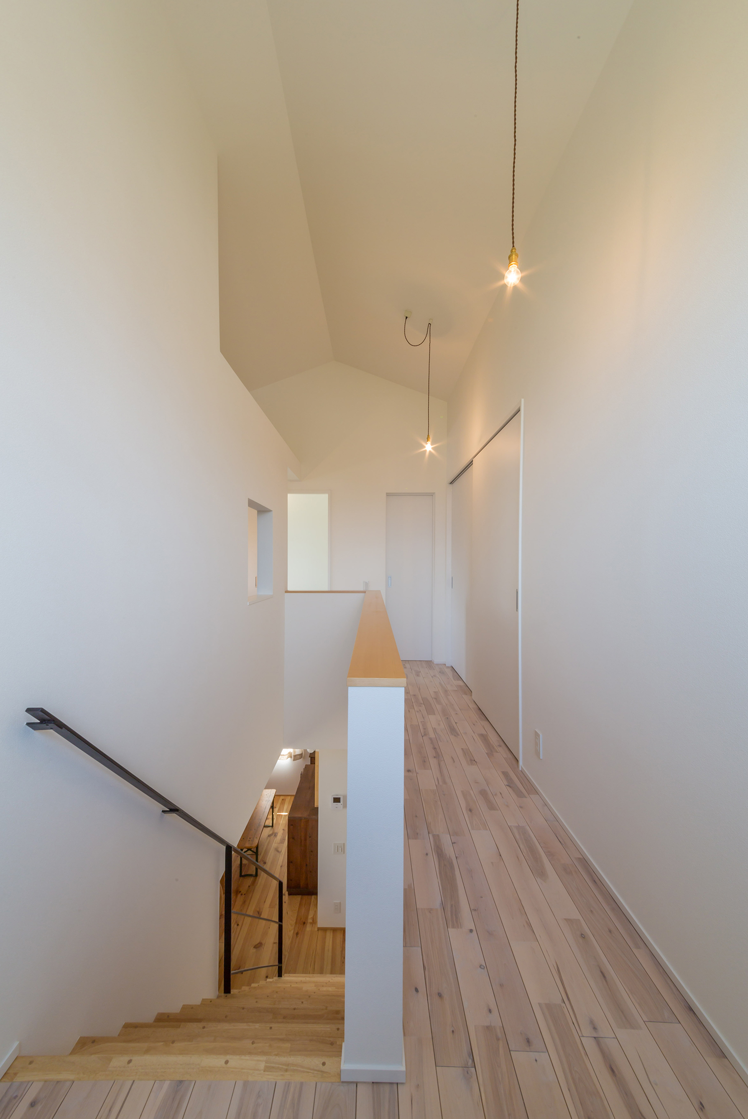 シンプルなペンダントライトを取り付けた白い壁の廊下・デザイン住宅