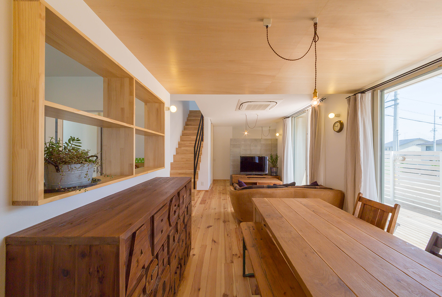 木のインテリアを中心としたシンプルなペンダントライトがあるLDK・デザイン住宅