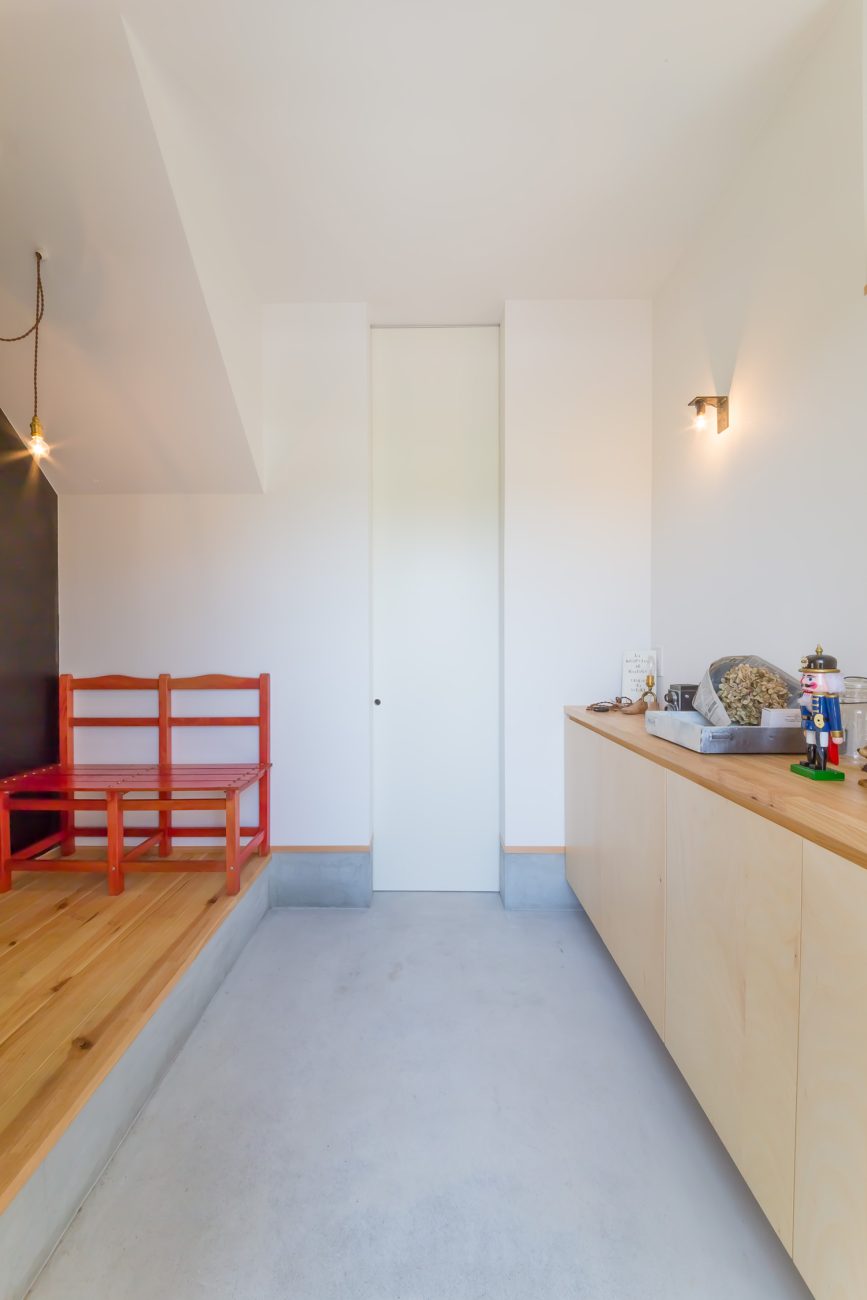 木のシューズボックスがあるモルタルの玄関・デザイン住宅