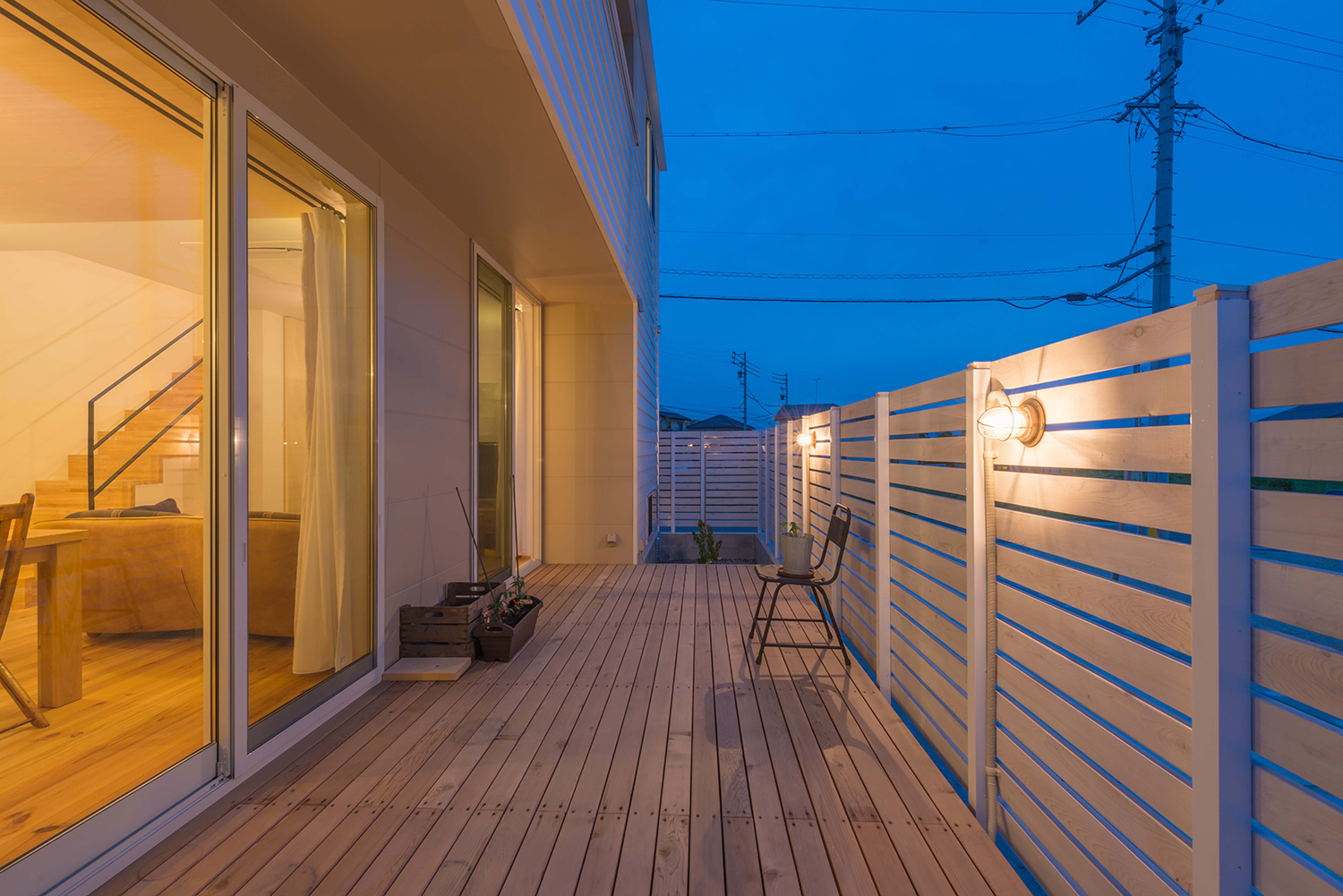 木の目隠し壁に照明を取り付けたログハウスのようなテラス・デザイン住宅