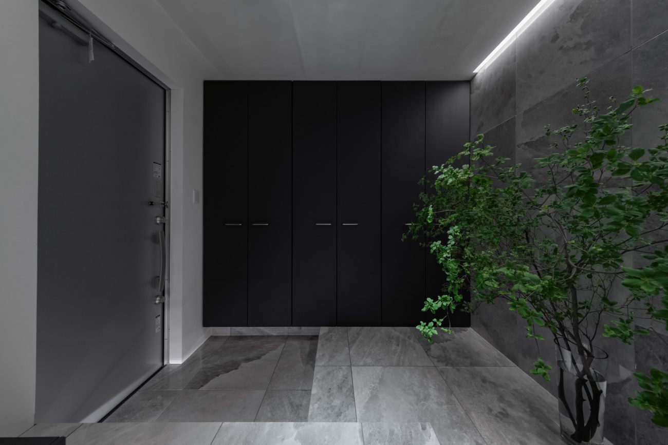 床と壁がグレーのタイルで、黒いシューズボックスやシンボルツリーがある玄関・デザイン住宅 注文住宅・デザイン住宅建築実例_『CASE749 dignified housing』_玄関