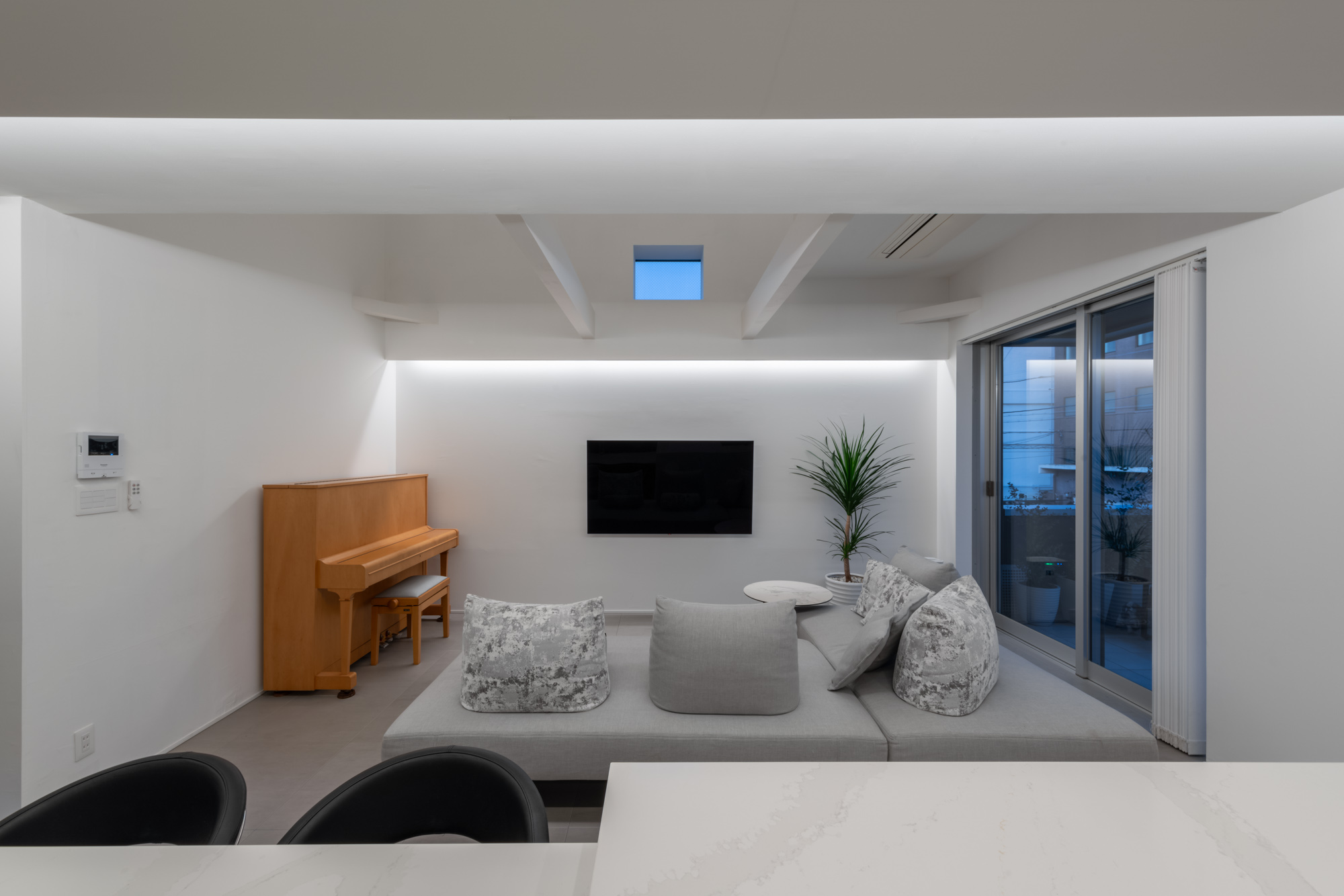 キッチンからソファーや木のピアノがあるリビングを見た様子・デザイン住宅 注文住宅・デザイン住宅建築実例_『CASE749 dignified housing』_LDK