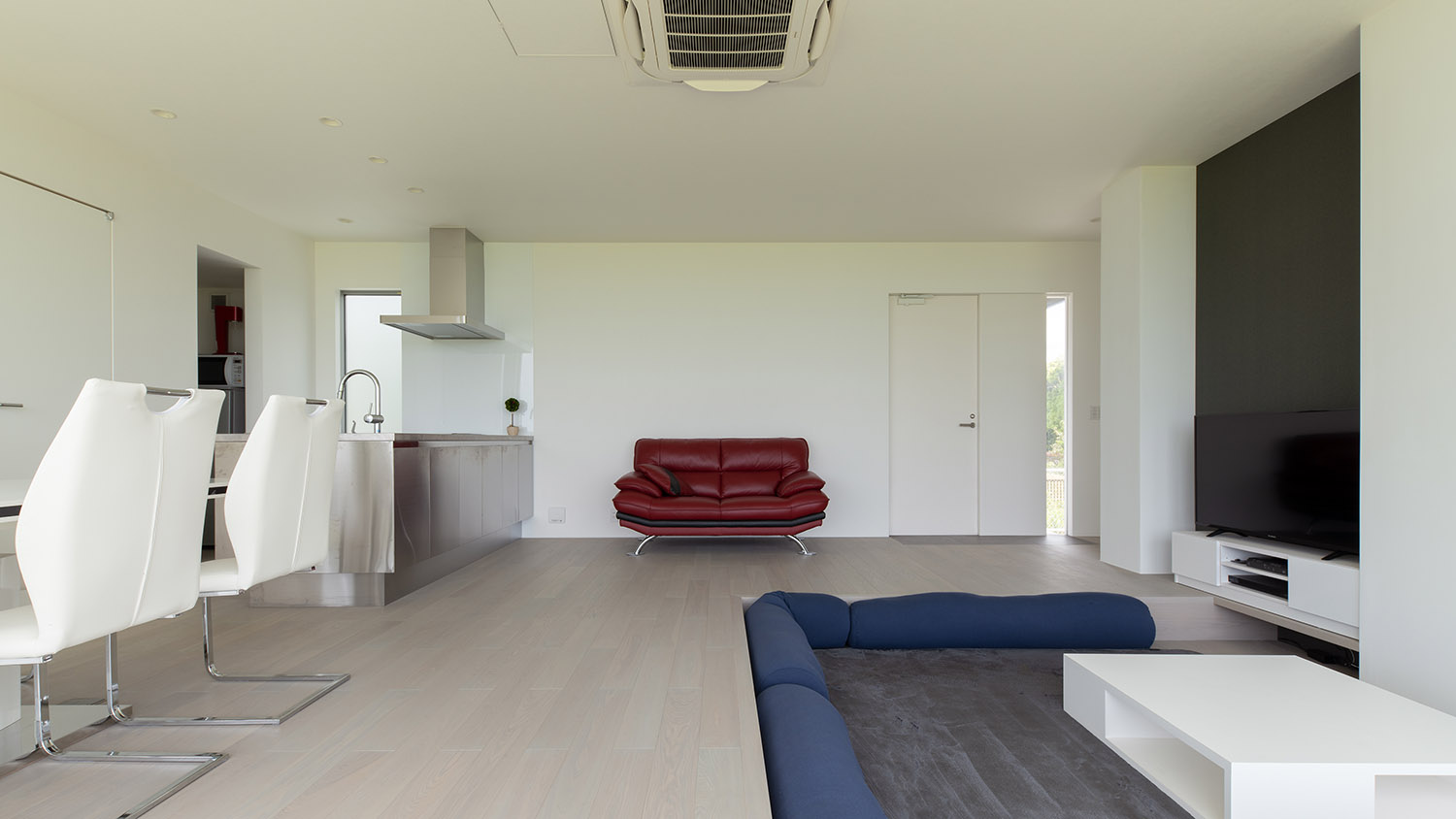 青いクッションのあるダウンリビングや赤いソファーがあるLDK・デザイン住宅 注文住宅・デザイン住宅建築実例_『CASE750 WHITE　GATE』_LDK