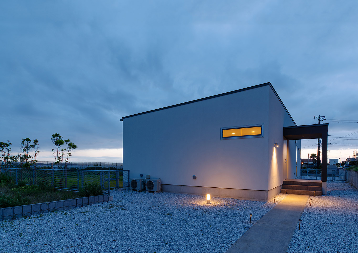 壁や地面に取り付けられた屋外照明に照らされるスリット窓がある住宅の外観・デザイン住宅 注文住宅・デザイン住宅建築実例_『CASE750 WHITE　GATE』_外観