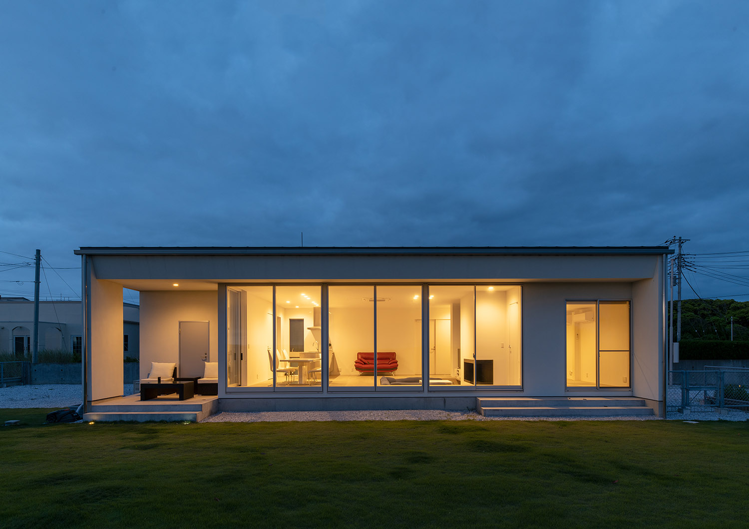 芝生に面する大きな窓から室内の明かりが漏れる平屋住宅の外観・デザイン住宅 注文住宅・デザイン住宅建築実例_『CASE750 WHITE　GATE』_外観