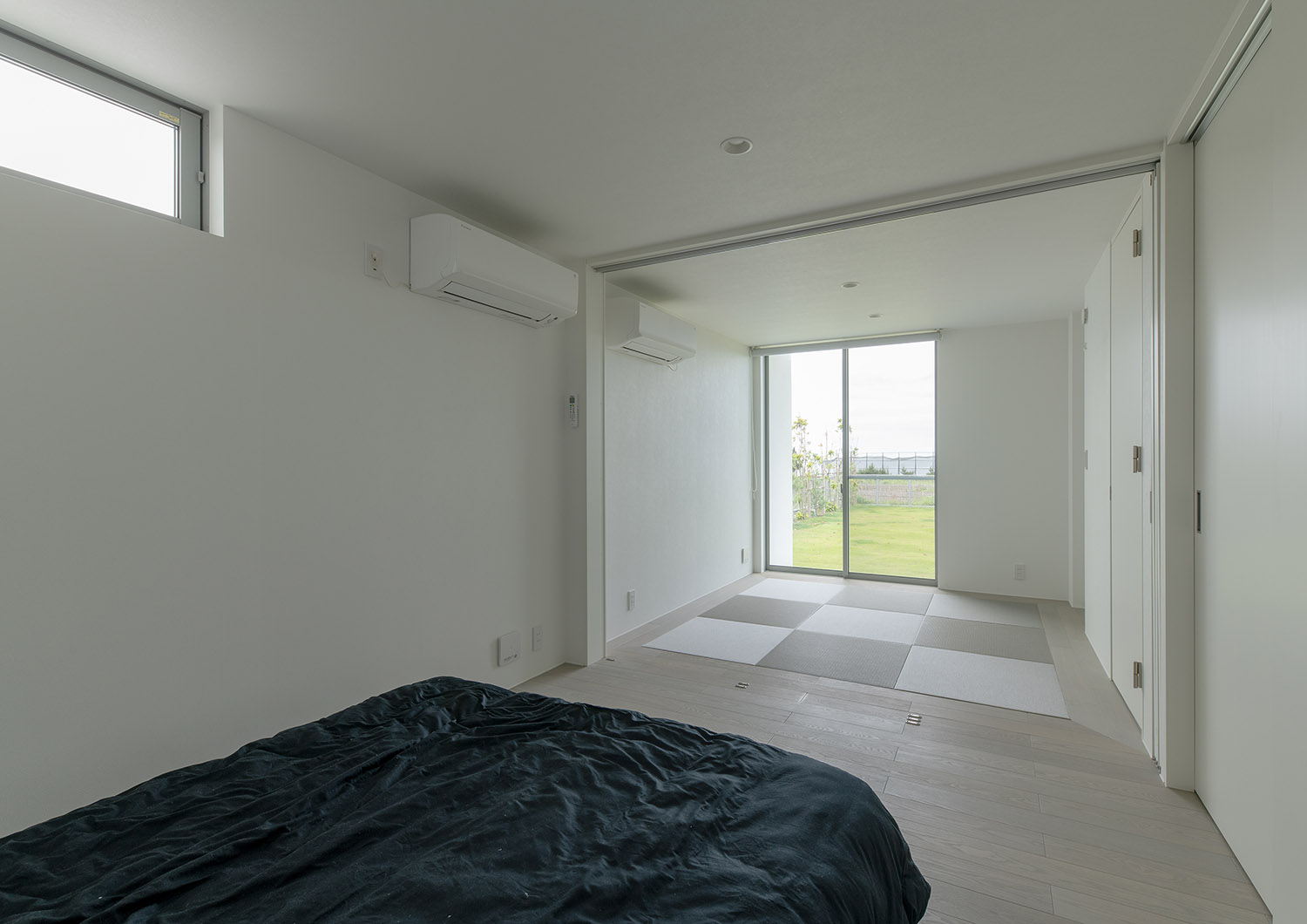 黒いベッドのある寝室から和室や芝生の庭が見える様子・デザイン住宅 注文住宅・デザイン住宅建築実例_『CASE750 WHITE　GATE』_和室