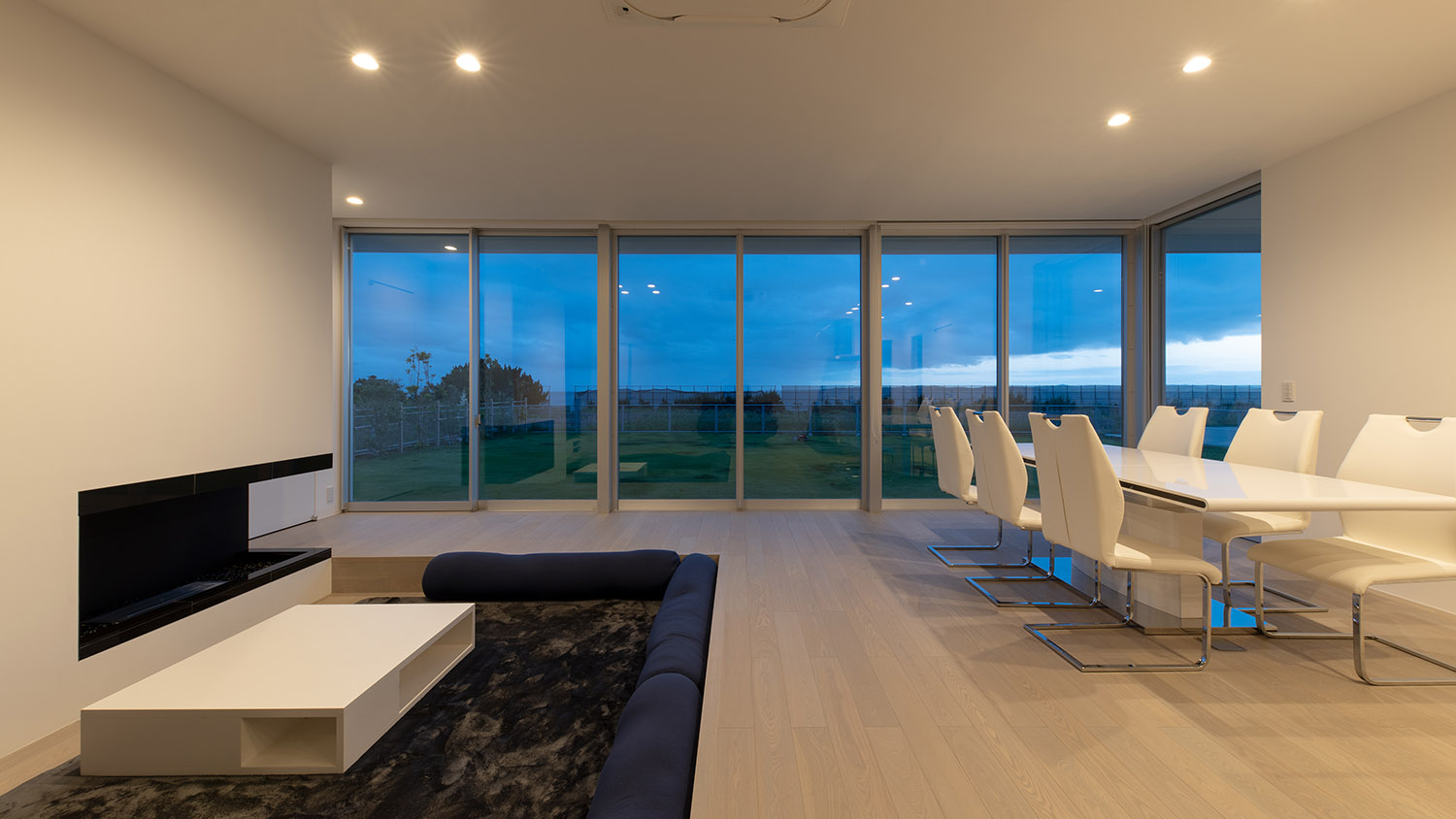 ダウンライトによって照らされたLDKから芝生の庭が見える様子・デザイン住宅 注文住宅・デザイン住宅建築実例_『CASE750 WHITE　GATE』_LDK